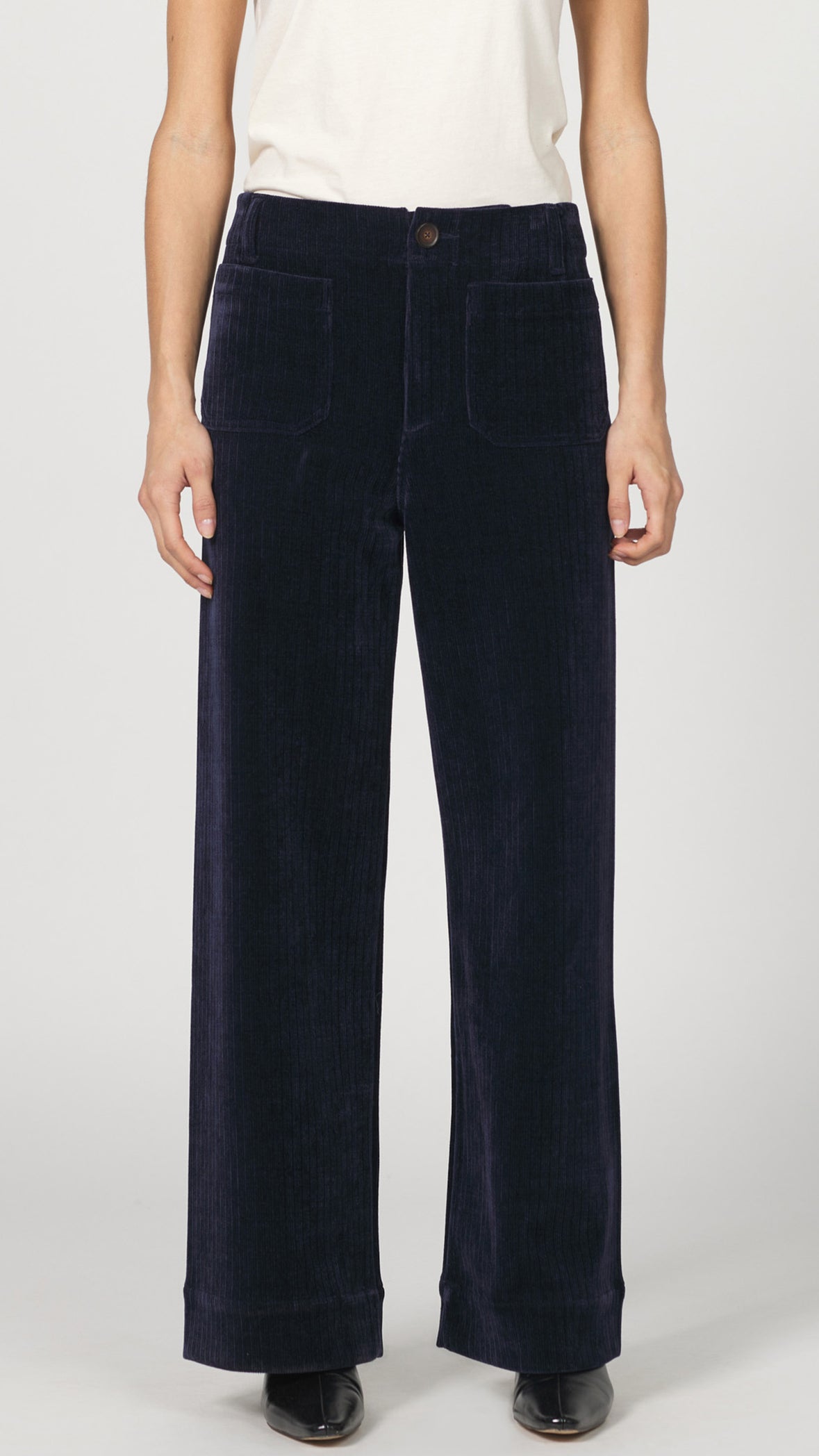 Front view of black iris wide-wale corduroy pants showing the front patch pockets and clean hem with black kitten heels