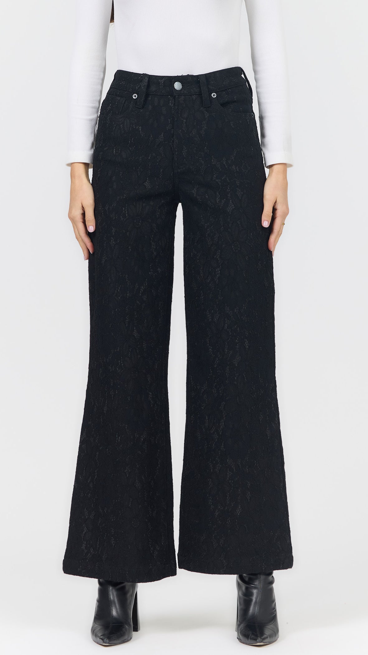 Front view of black lace wide leg pants showing the allover lace pattern, five-pocket styling, and black ankle boots