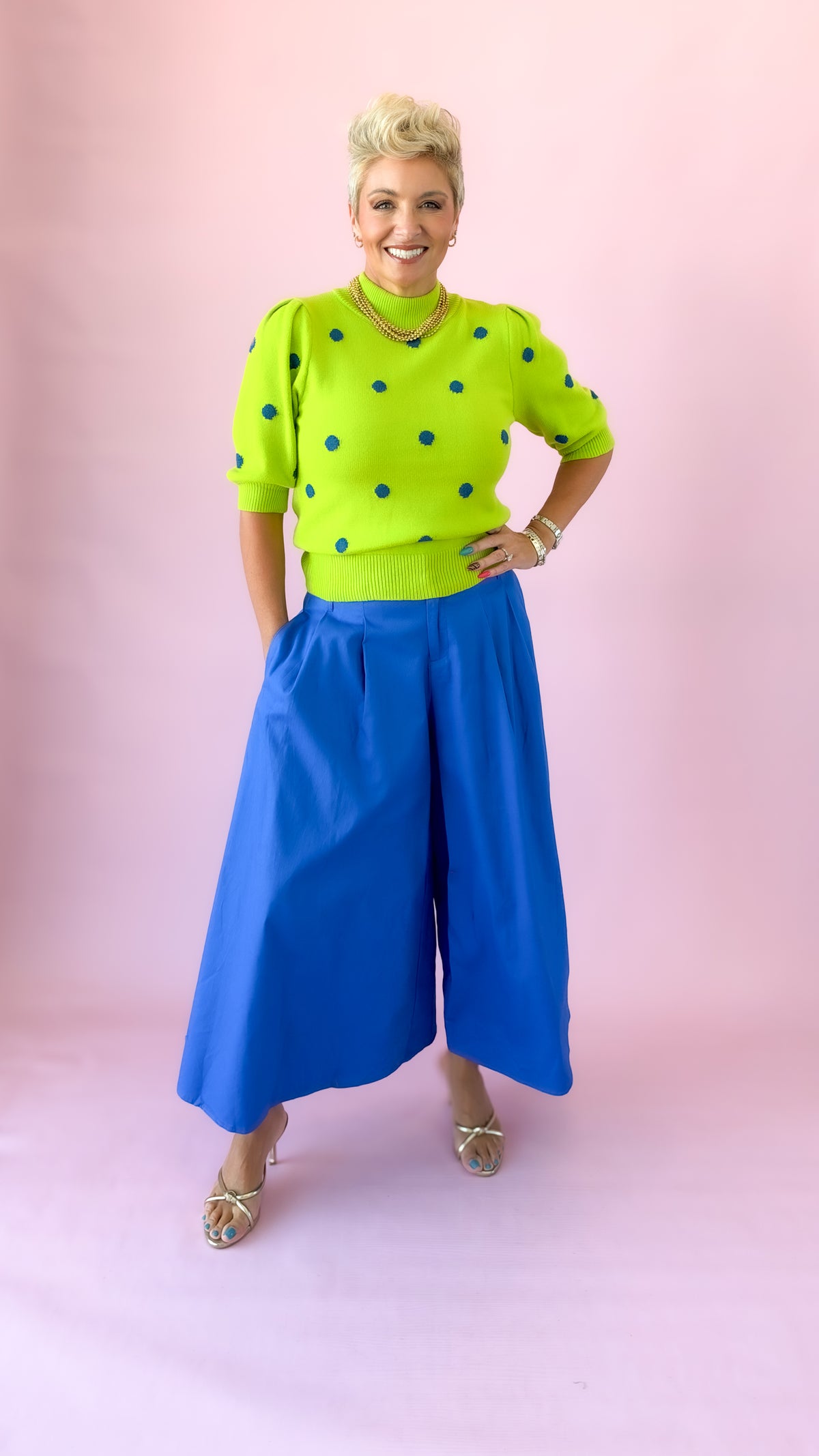 Cobalt blue pleated culotte pants worn with hands on hips