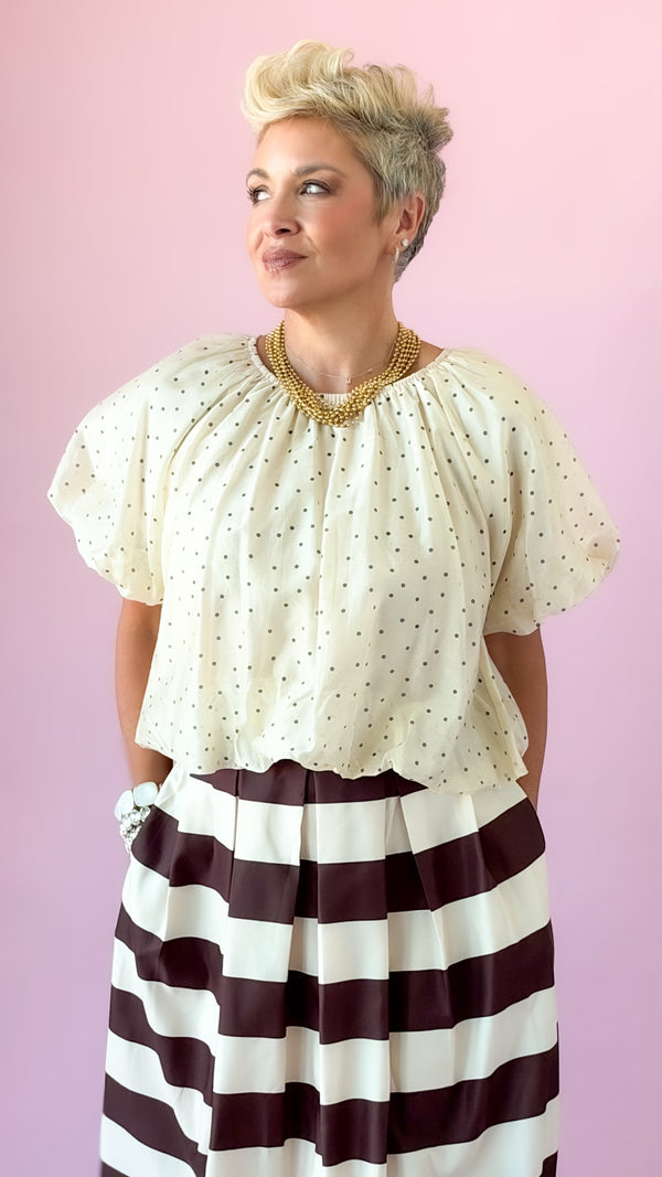 Ivory flutter puff sleeve top with dotted texture, tucked into a striped skirt