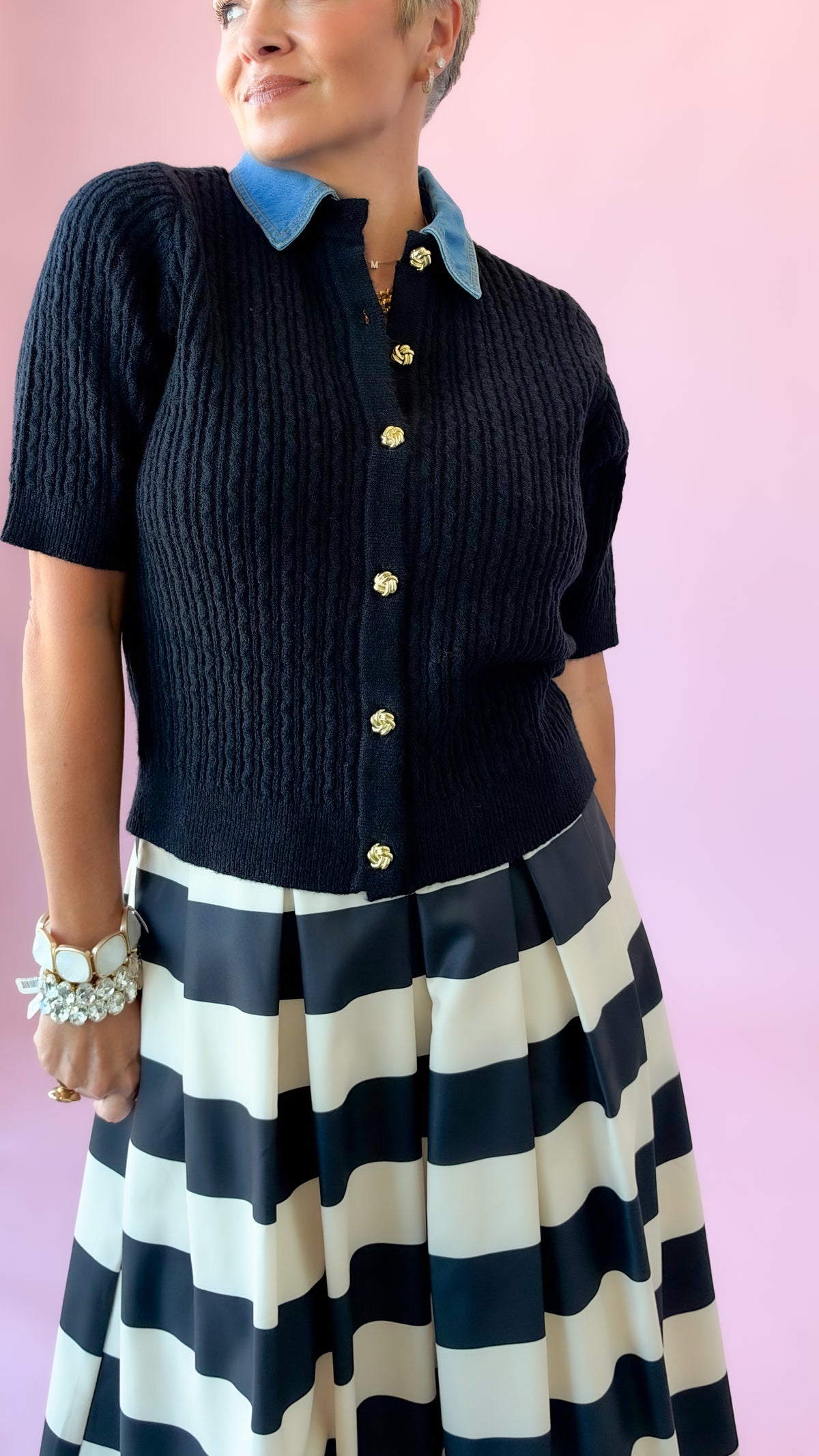 Close-up of black short sleeve cable knit sweater with denim collar and gold buttons