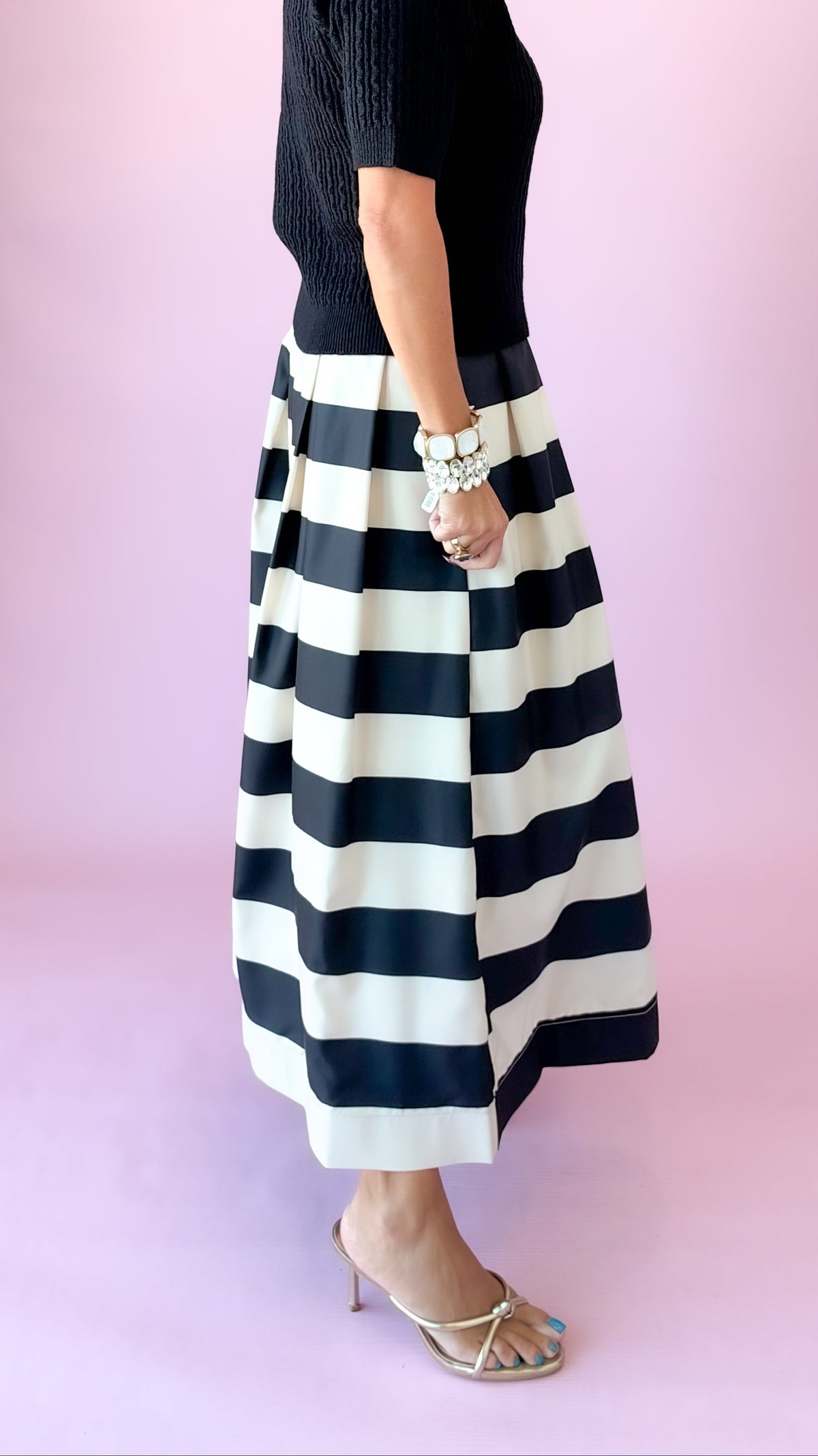Side close-up of black and white striped pleated midi skirt showing its full volume