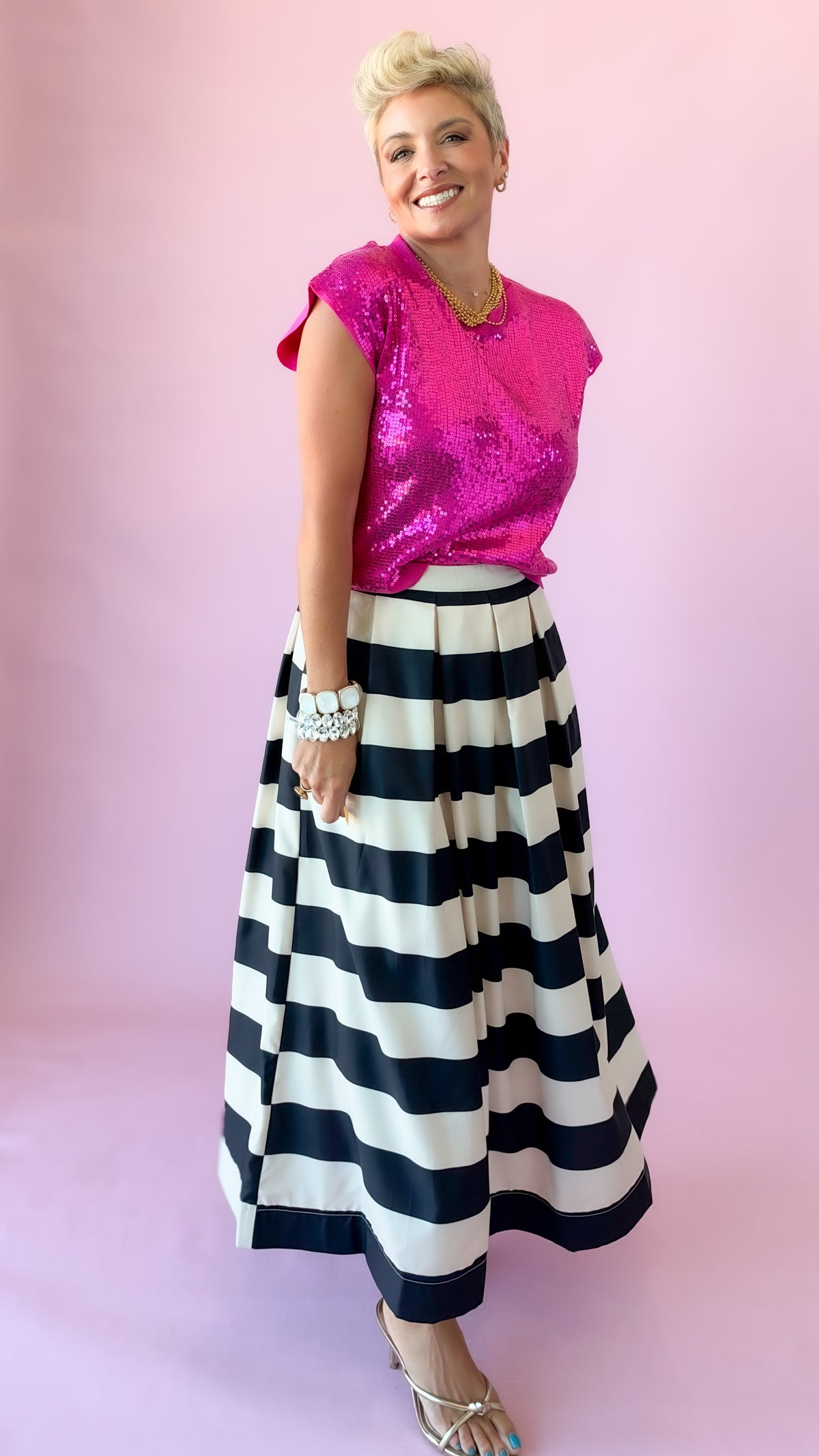 Full-length view of hot pink Sierra sequin top with striped pleated skirt