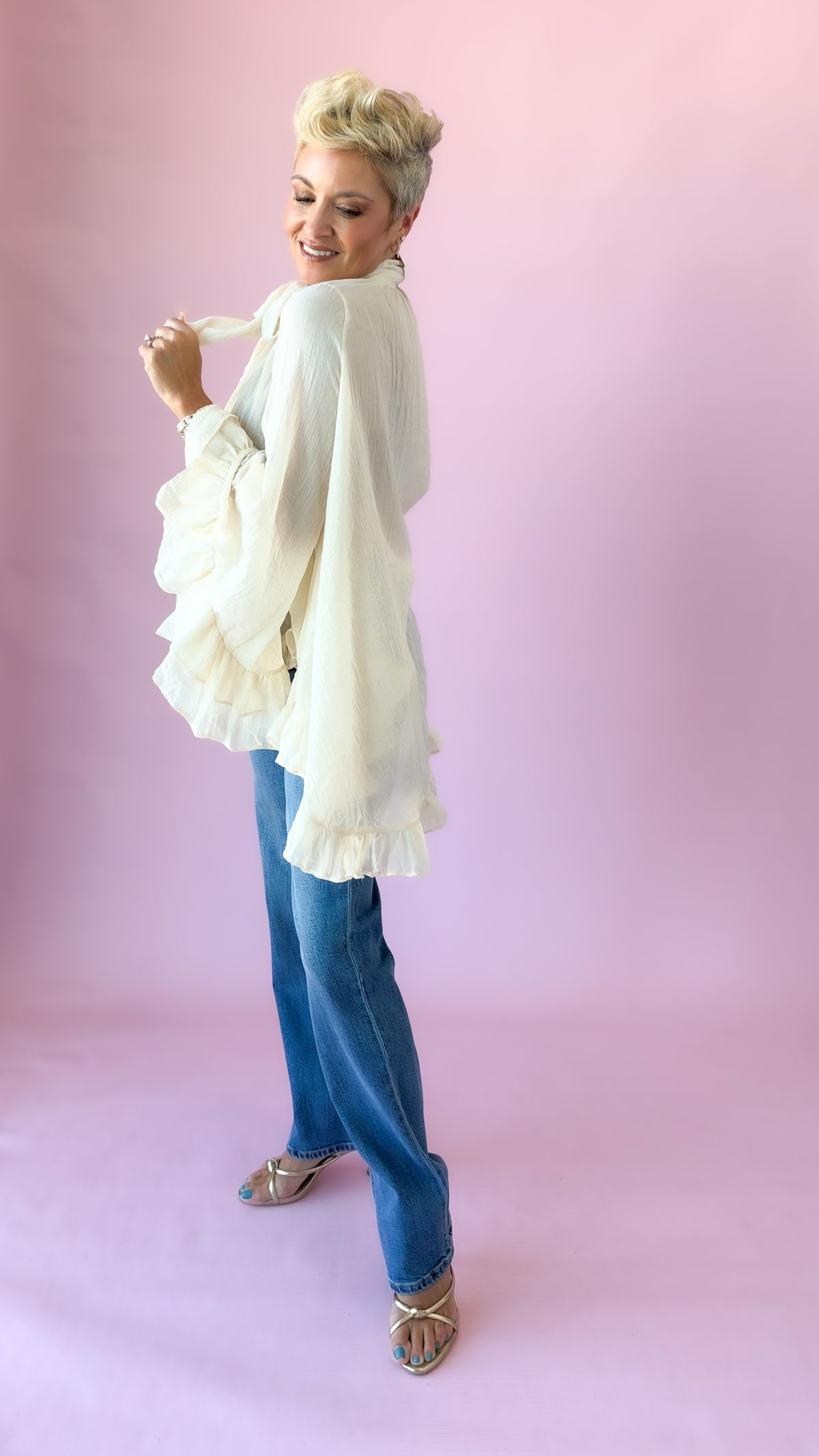 Side back view of cream oversized blouse with ruffled bell sleeves