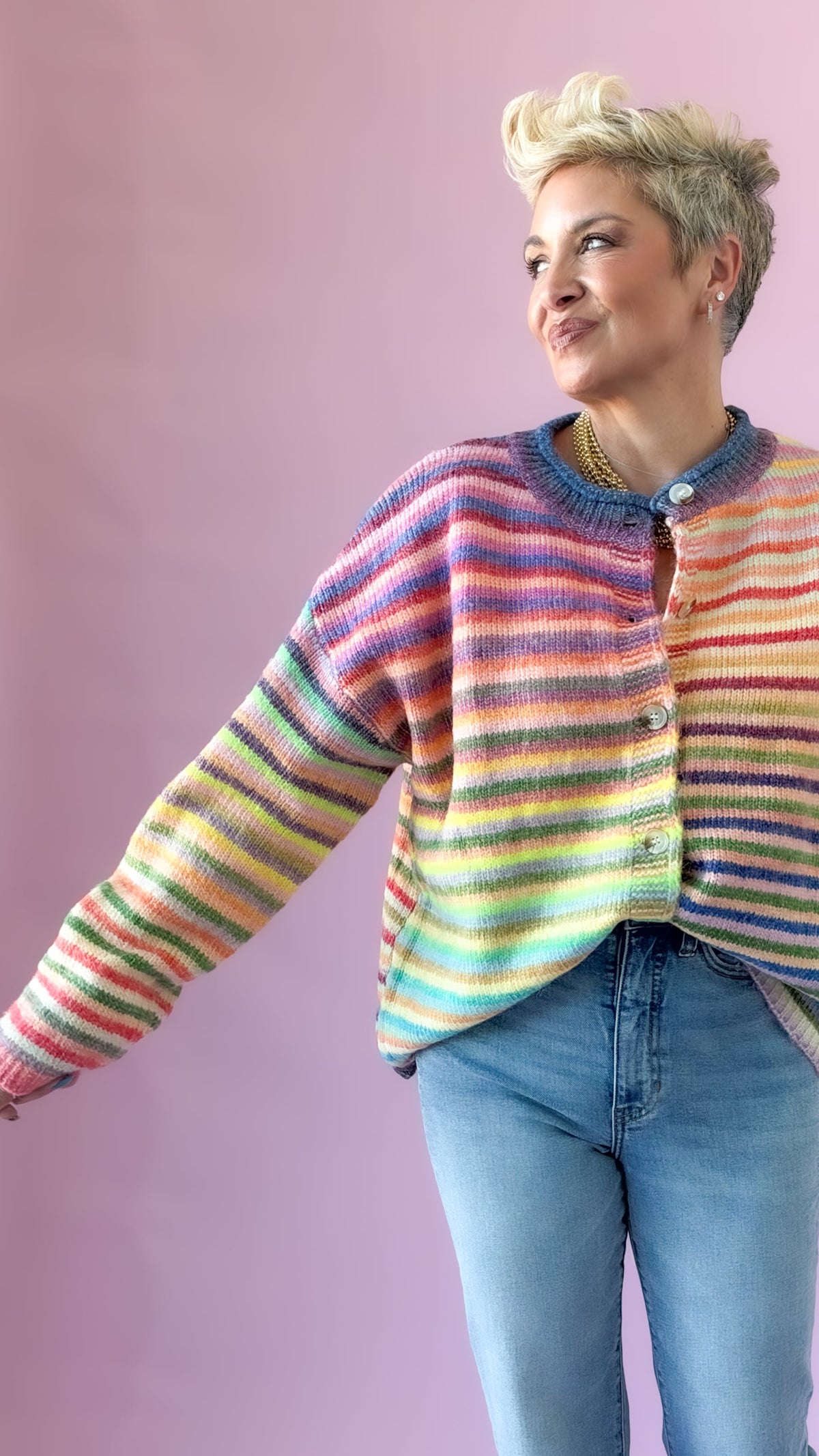 Rainbow striped button-up cardigan shown with one arm extended