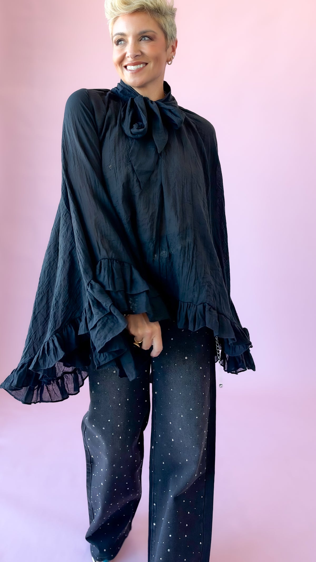 Black oversized sheer blouse with neck bow and ruffle hem, styled with dark jeans