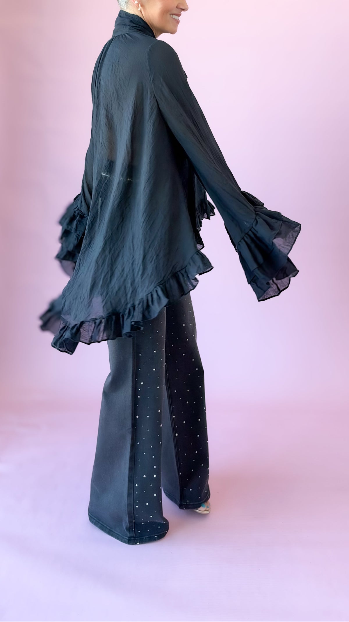 Side view of black oversized bow blouse showing ruffled sleeves