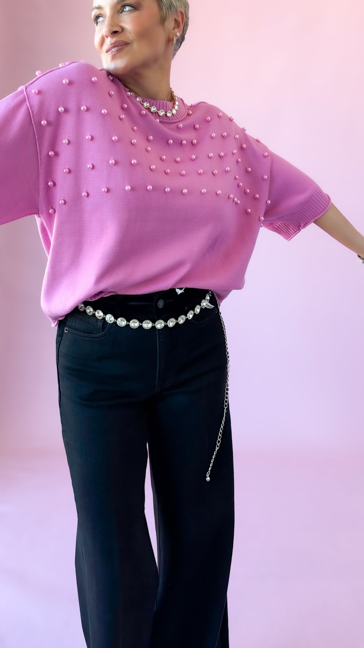 Pink short sleeve crewneck sweater with pearl embellishments and black pants