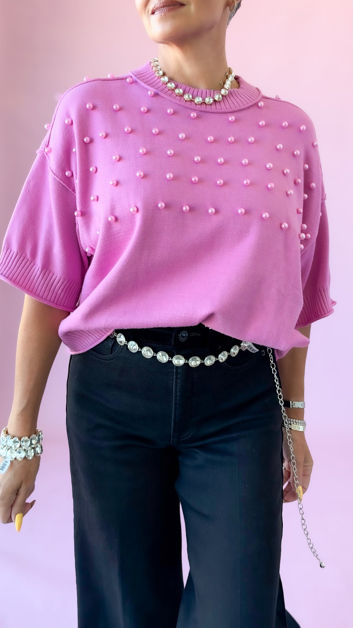 Pink pearl embellished sweater with black flare jeans, front view