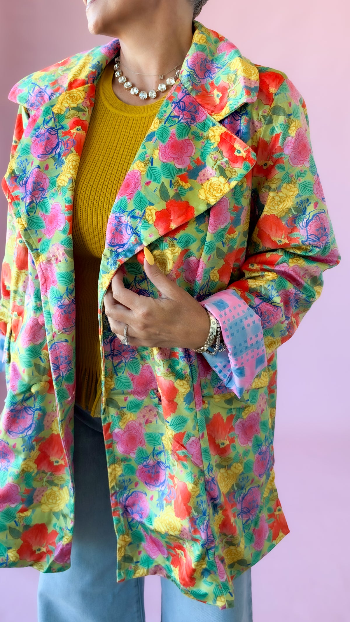 Close-up of mustard Chelsea flutter sleeve sweater under a bright floral jacket