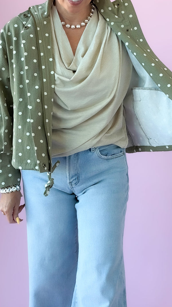 Beige cowl neck cap sleeve top layered under an olive polka dot jacket with jeans