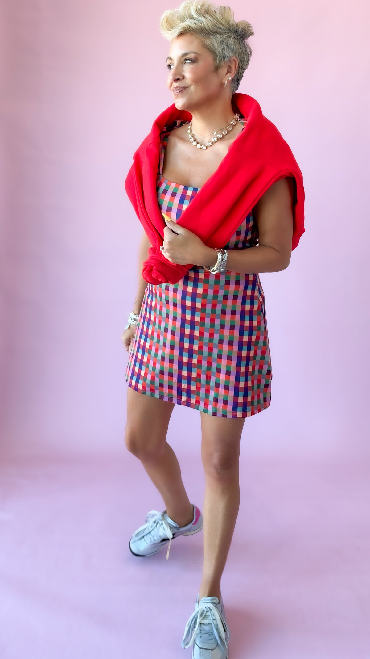 Close-up of multicolor gingham mini dress with red sweater draped over shoulders