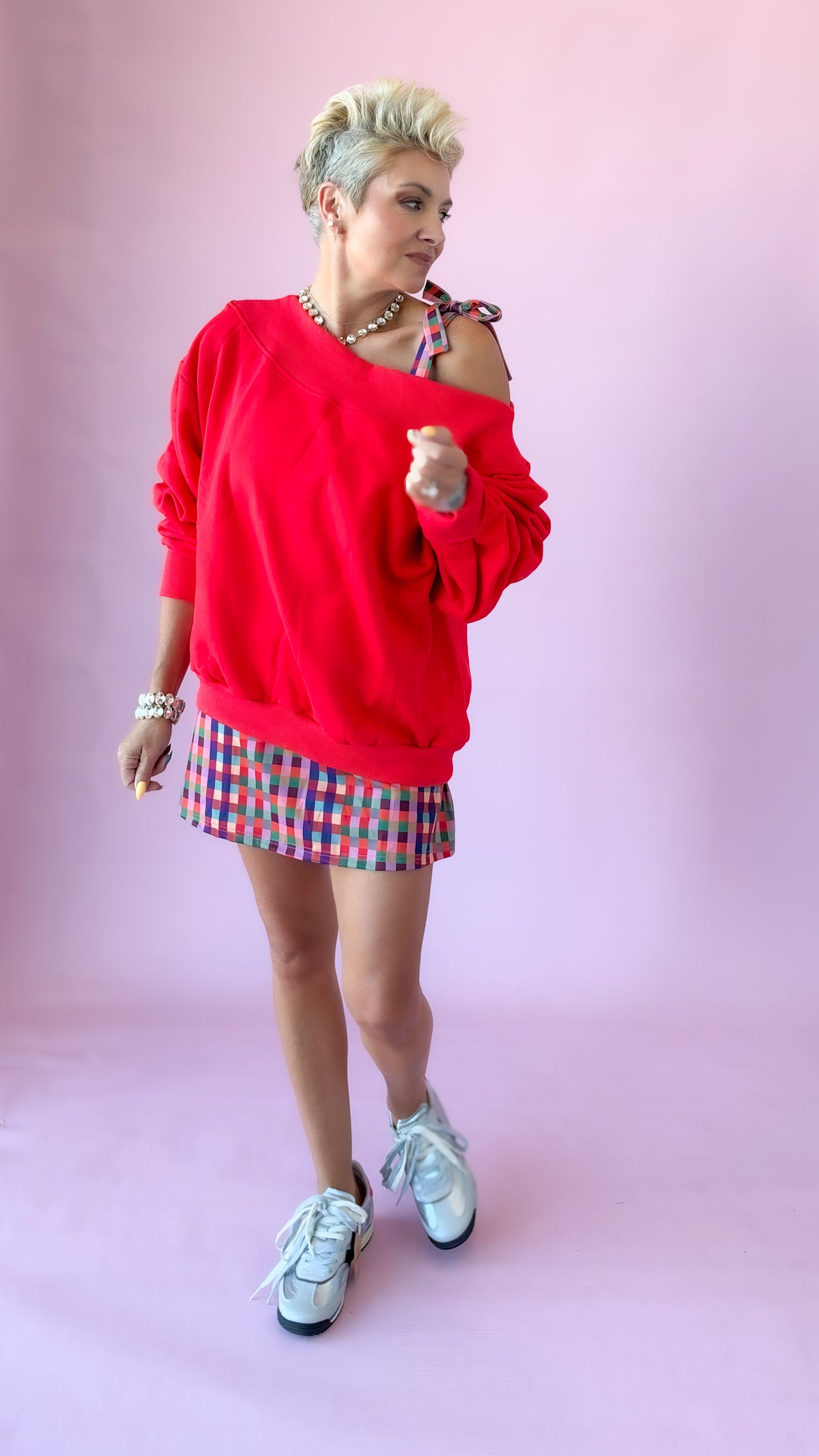 Full-length view of red Harlow sweatshirt with checked shorts and sneakers