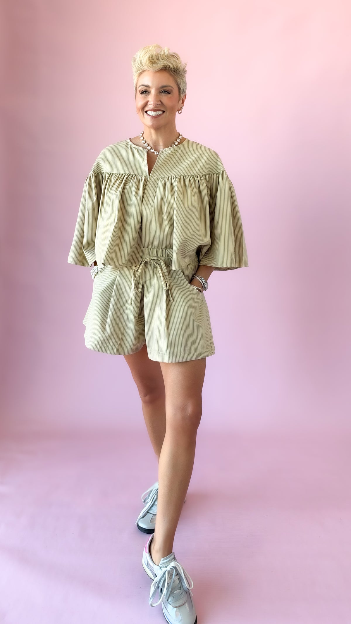 Full-length view of beige striped shorts and matching top with sneakers