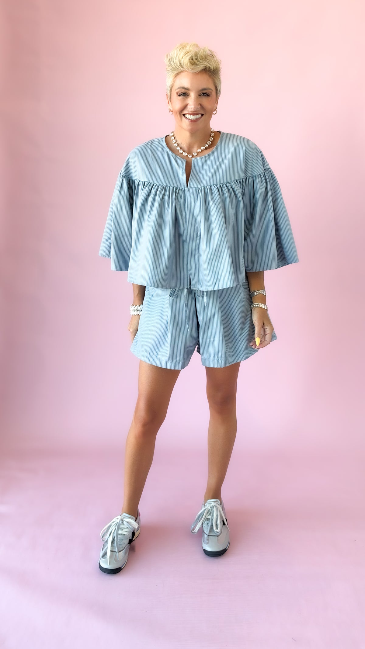 Full-length view of light blue striped swing cape top set with sneakers