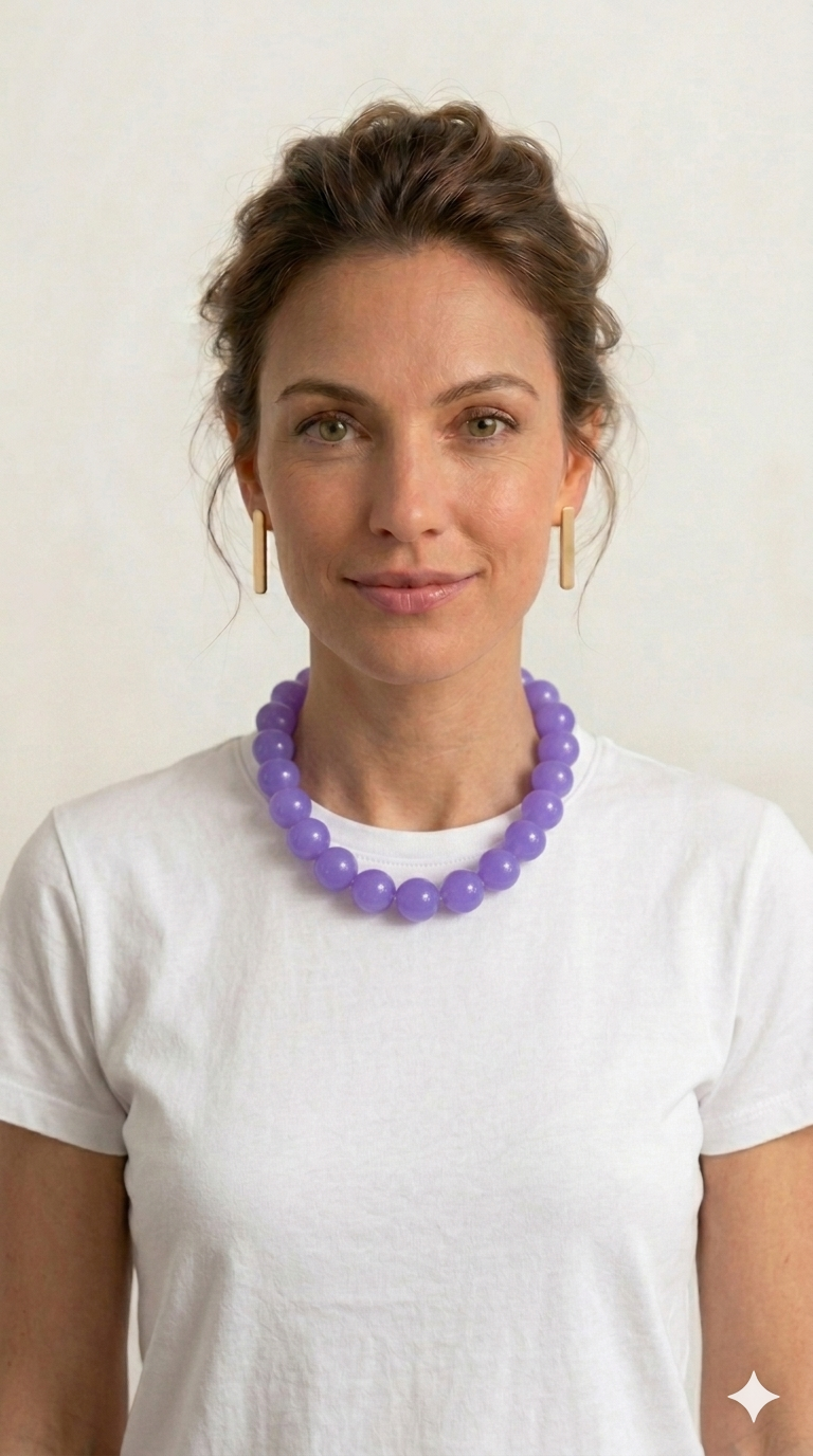 Woman wearing a purple necklace against a plain background