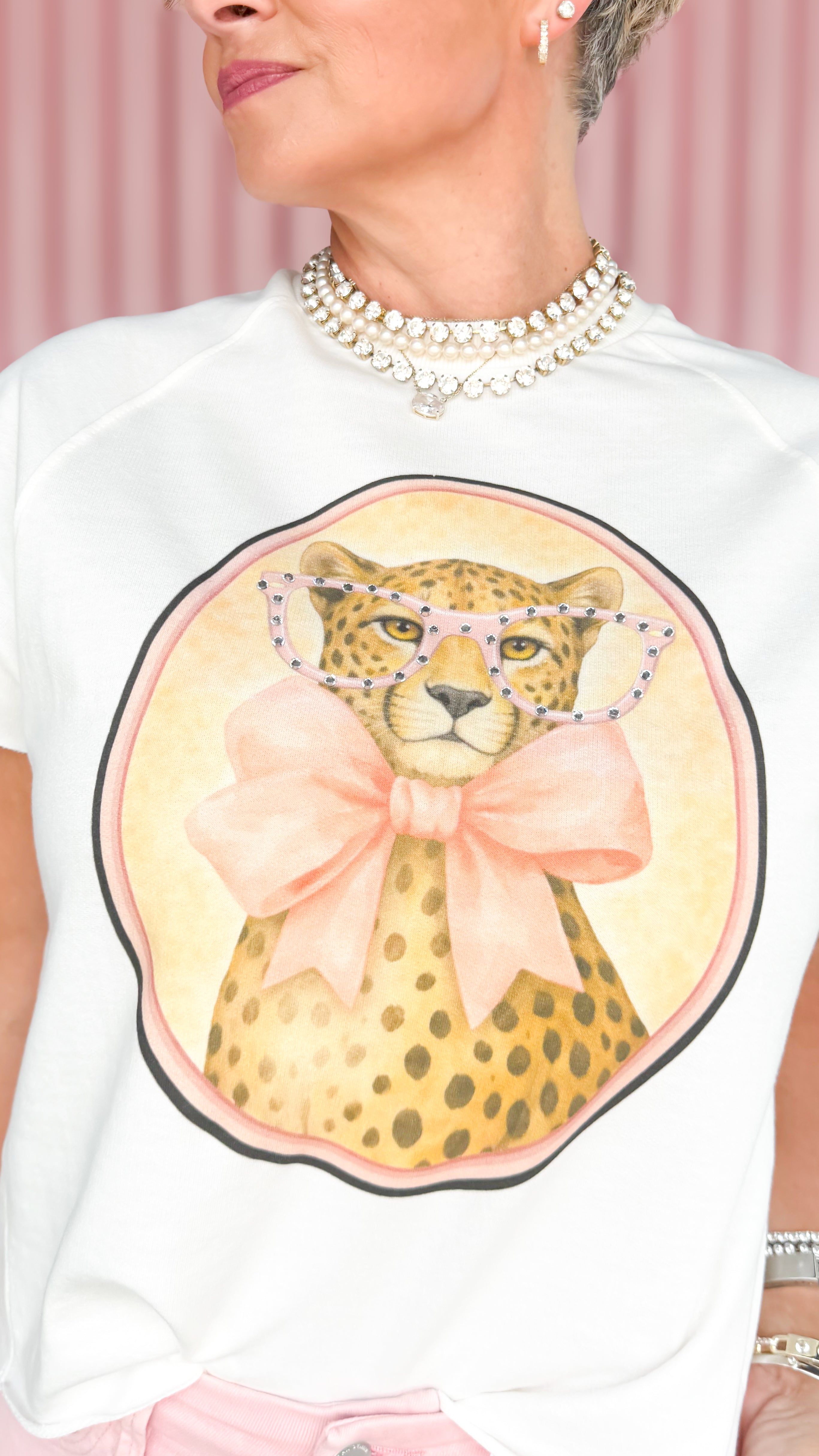 White top with a leopard graphic and pink bow on a light pink background
