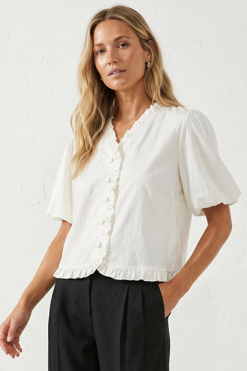 Woman wearing a white blouse with black pants against a white background