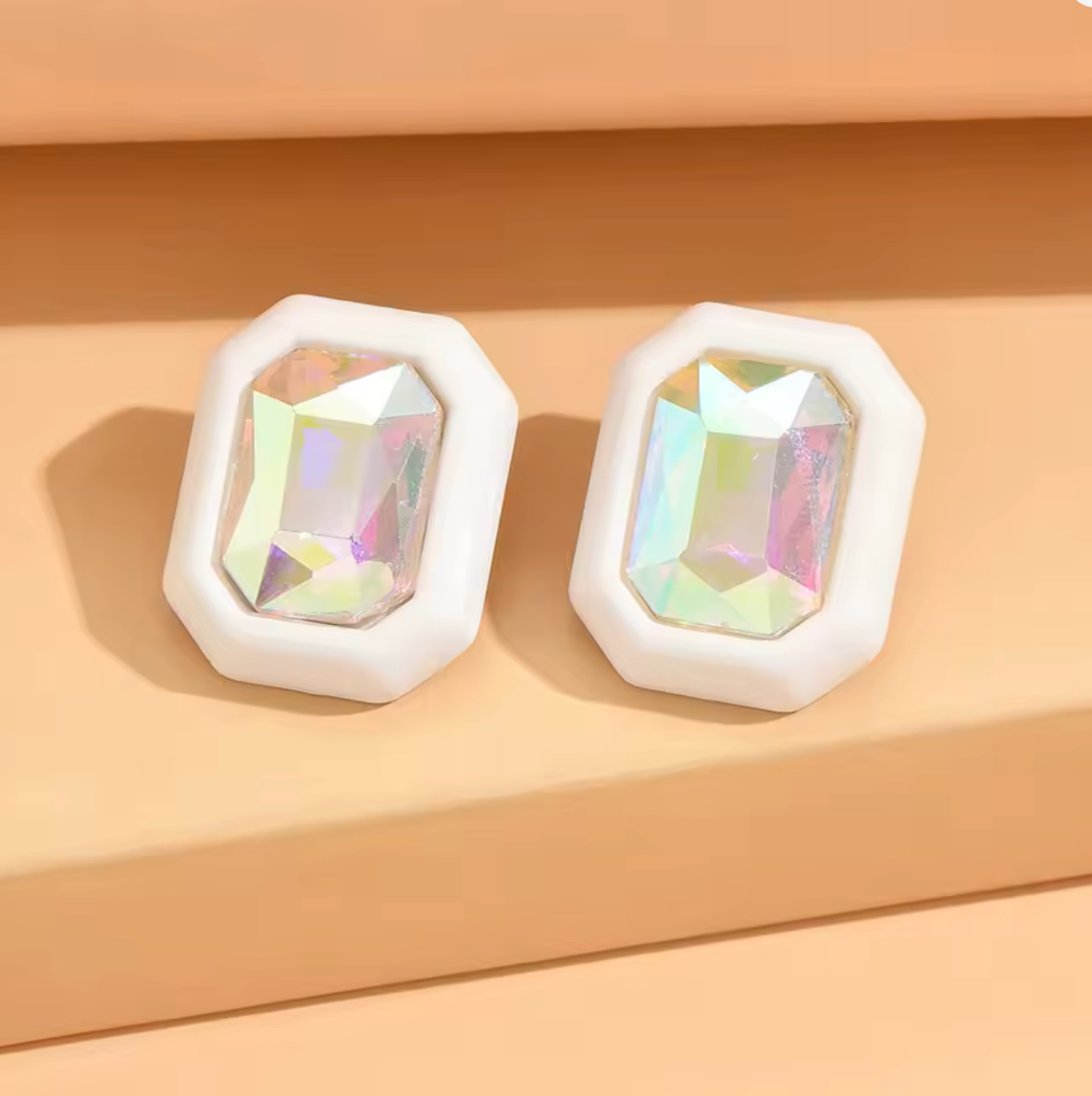 Pair of earrings with iridescent gemstones on a beige background