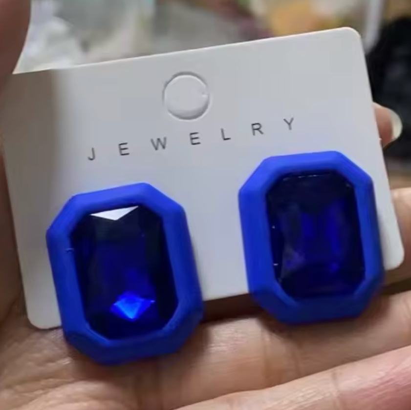 Blue gemstone earrings on a jewelry card held in a hand.