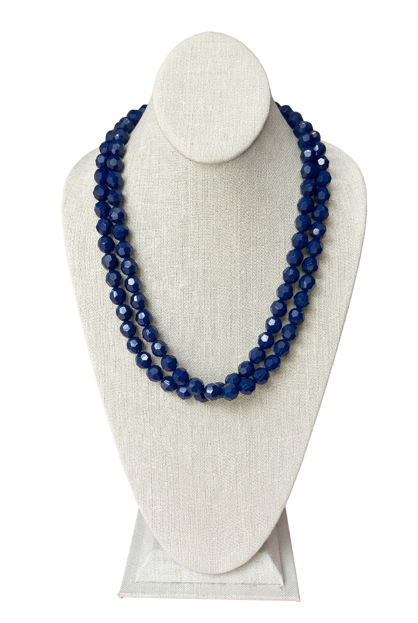 48-inch navy blue faceted bead necklace worn doubled in two layered strands on a beige linen jewelry bust