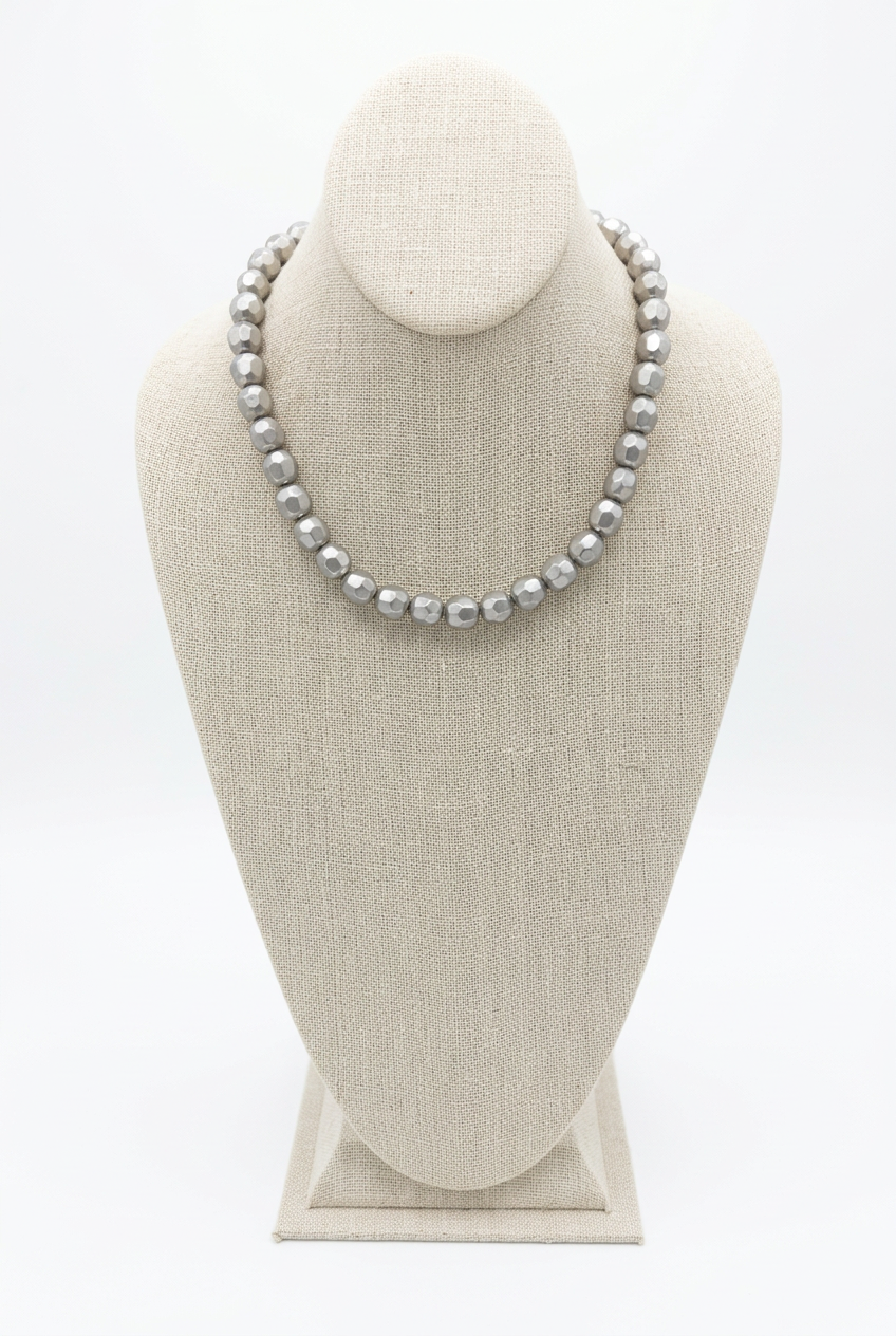 18-inch silver faceted bead necklace displayed on a beige linen jewelry bust