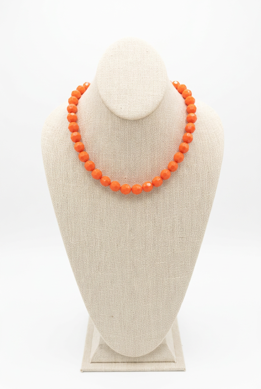 18-inch neon orange faceted bead necklace displayed on a beige linen jewelry bust
