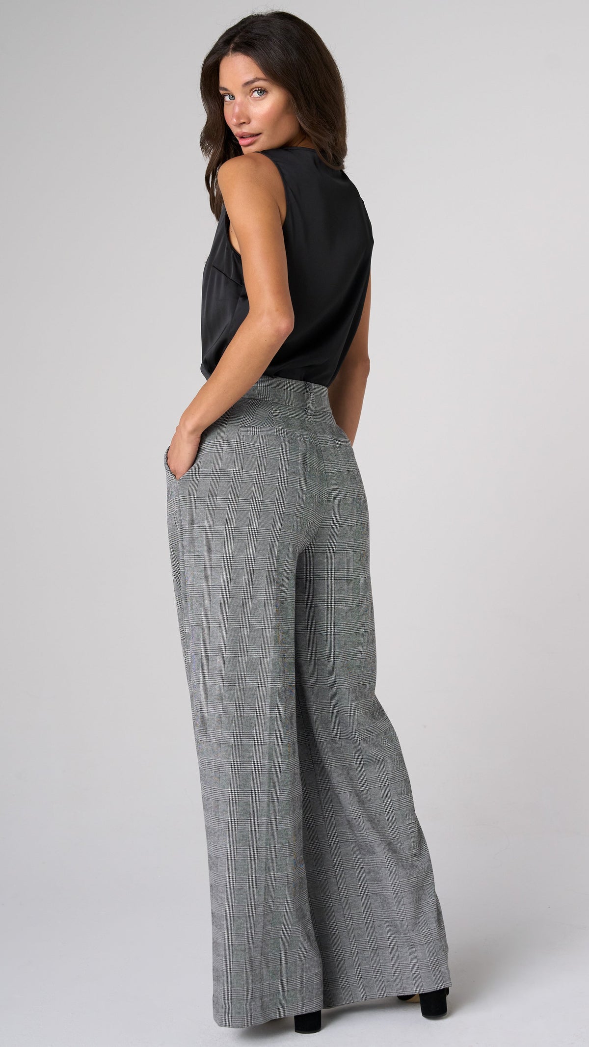 Over-the-shoulder side back view of model in glen plaid Brooke high rise wide leg trousers with black sleeveless top