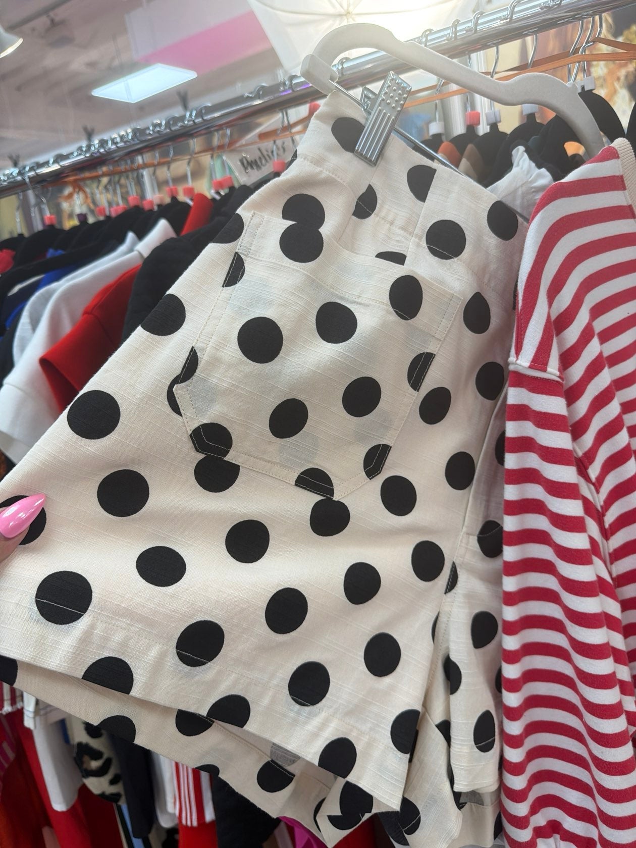 Black polka dot fabric on a hanger with a striped shirt in the background