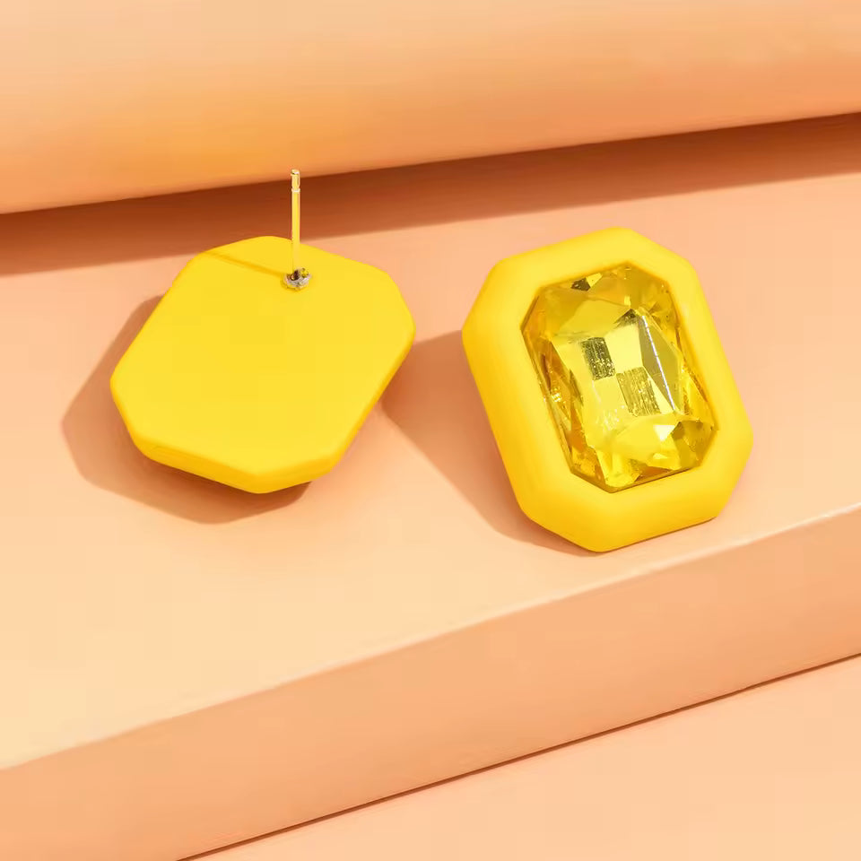 Yellow geometric earrings on a peach background