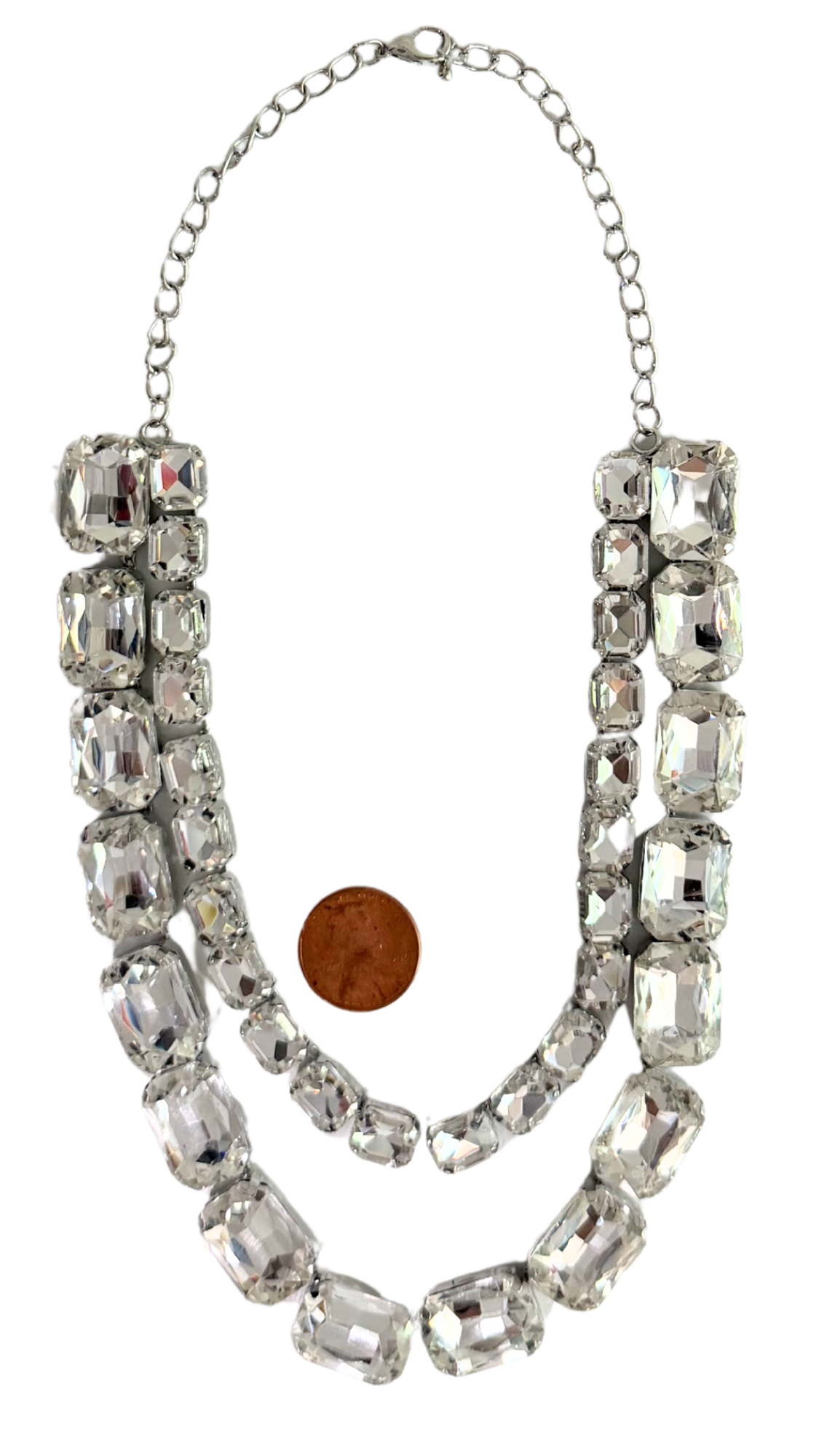 Necklace with large crystals next to a penny for scale on a white background