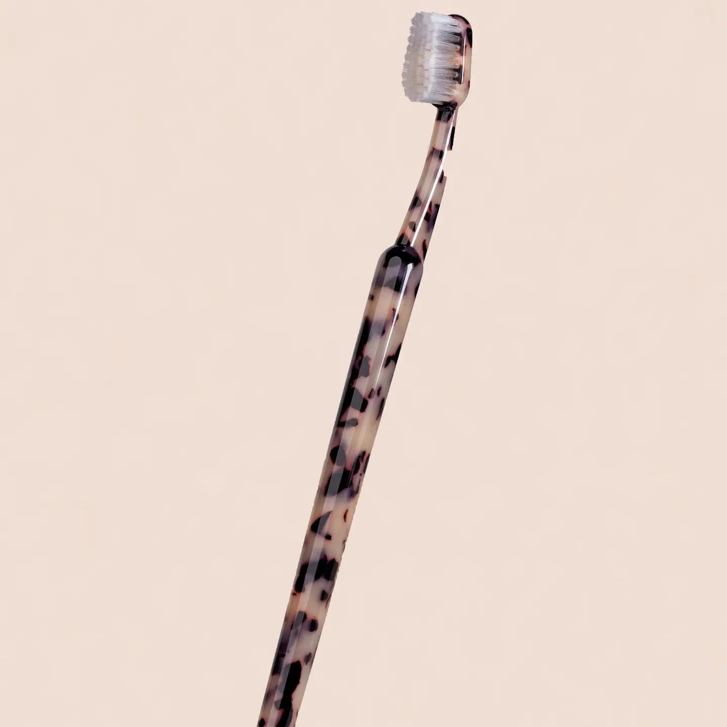 Tortoiseshell-patterned toothbrush on a beige background