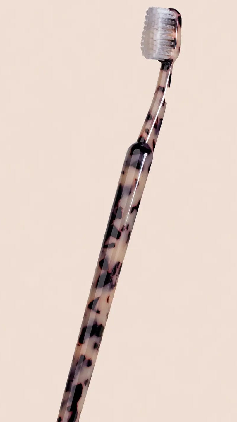 Tortoiseshell-patterned toothbrush on a beige background