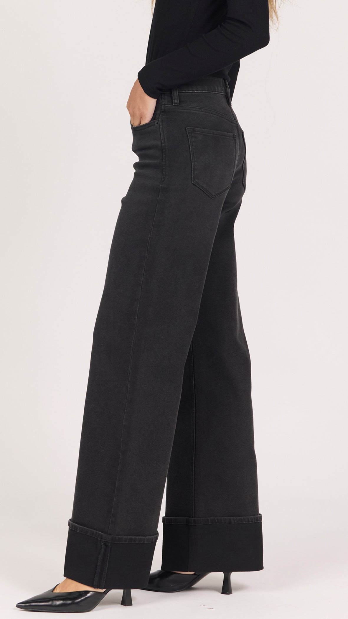 Three-quarter side view of midnight Fiona jeans showing the deep cuffed hem and black pointed heels