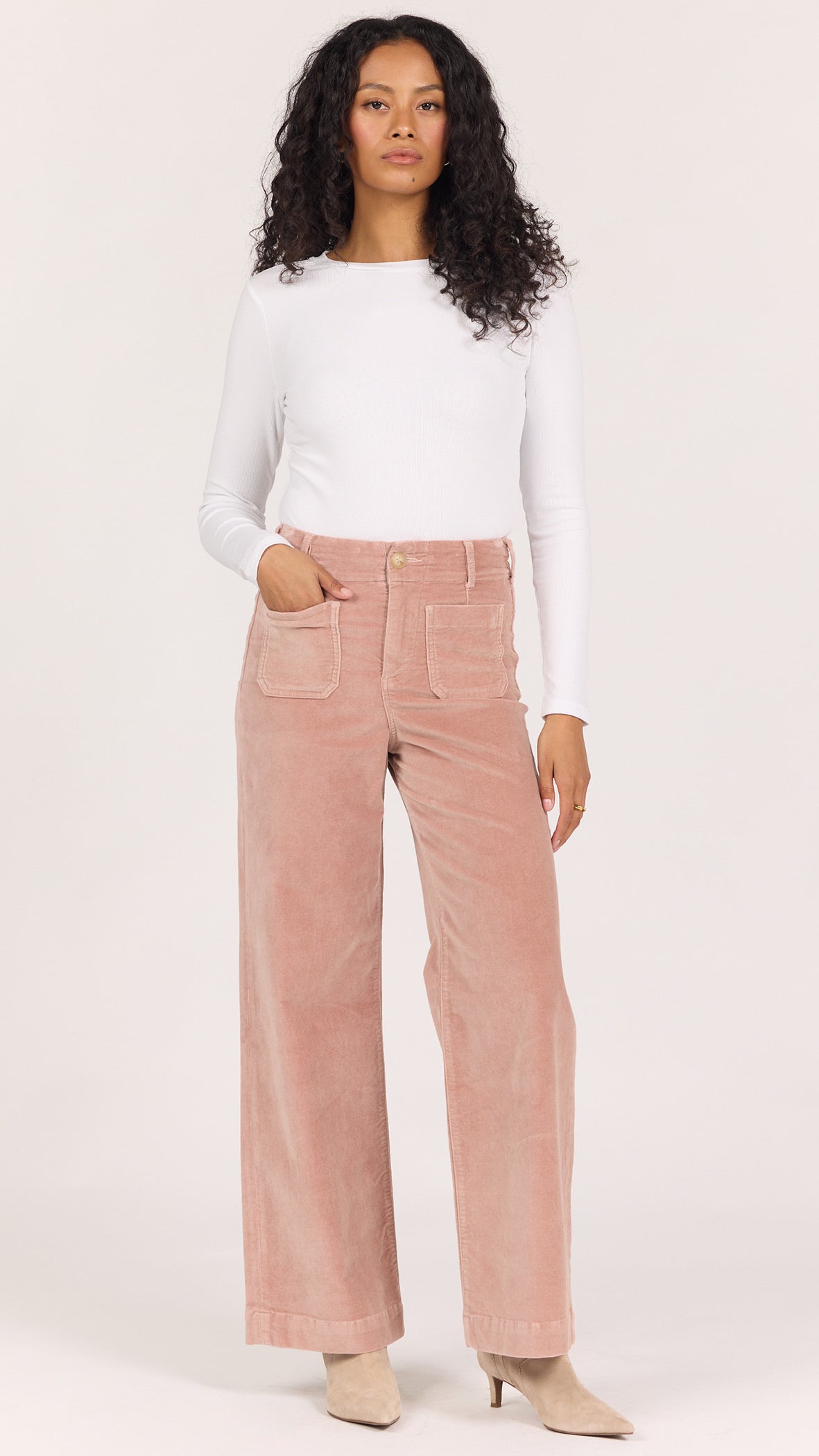 Full-length front view of Dear John Audrey corduroy wide leg pants in soft latte dusty rose worn with a white long sleeve and cream ankle boots