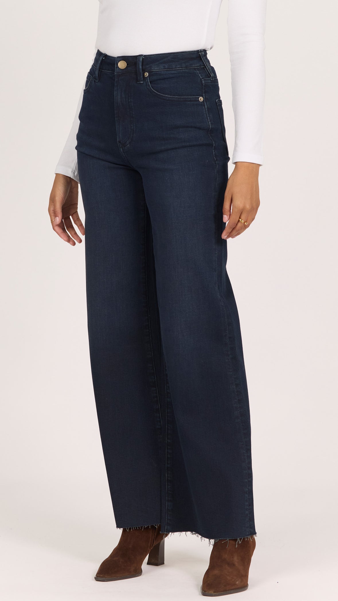 Three-quarter side view of inkwell Fiona jeans showing the sweeping wide leg and brown suede heeled ankle boots